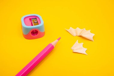 Parlak sarı bir yüzeye renkli bir bileyiciyle kırmızı kalem ve kıvrımlı talaşlar. Okul temaları için temiz yaratıcı daire. 