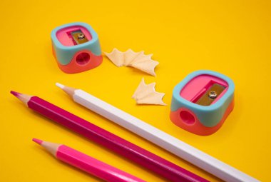 Pembe-mavi kalemli kırmızı-beyaz kalemlerin yaratıcı üst görüntüsü temiz sarı arka planda. Okul ve öğrenim temaları için kırtasiye kompozisyonu. 