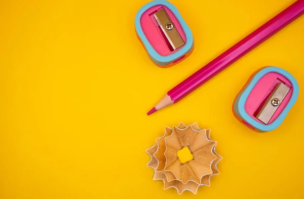 Düz keskinleştiriciler, kalem kırıntıları ve parlak sarı arka planda kırmızı bir kalem. Okul, sanat, eğitim ve yaratıcılık temaları için harika. 