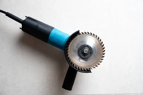 Close-up of a blue angle grinder with a circular cutting disc on a neutral background. Ideal for tool sales, DIY tutorials, hardware catalogs and safety guides