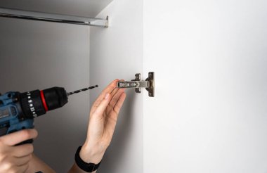 Eller matkapla duvara menteşe takıyor. DIY, inşaat, marangozluk ve onarım temaları için mükemmel. 