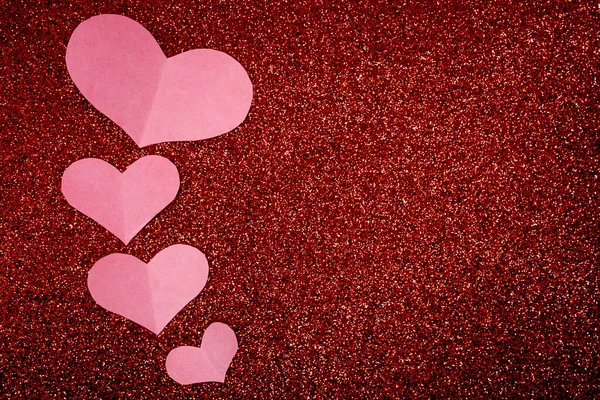 Kırmızı parıltılı arka planda yüzen yumuşak pembe kağıt kalpler. En az romantik Sevgililer Günü arkaplanı, aşk mesajları ve markalaşma için fotokopi alanı.