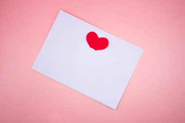 Pembe arka planda kırmızı kalbi olan en az beyaz kart. Sevgililer Günü, aşk mesajı ve romantik selamlama konsepti.