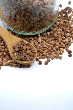 Buckwheat grains with glass jar isolated on white. Organic gluten-free food, sustainable kitchen and clean eating concept.