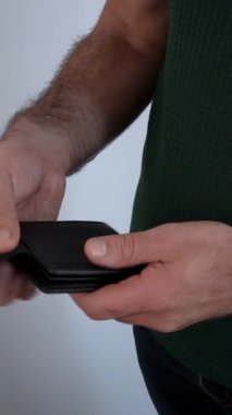 Siyah bir cüzdan açıp yüz dolarlık banknot gösteren bir adamın yakın çekim videosu. Finans, gelir, ödeme, tasarruf ve kişisel refah yönetimi kavramı.