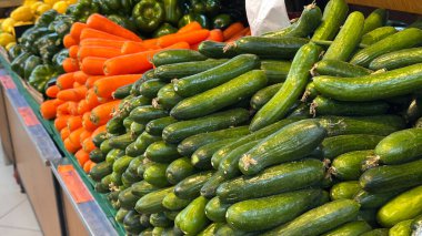 Markette taze salatalık, turuncu parlak havuç ve yeşil dolmalık biber içeren bol miktarda taze ürün sergileniyor. Yüksek kalite fotoğraf