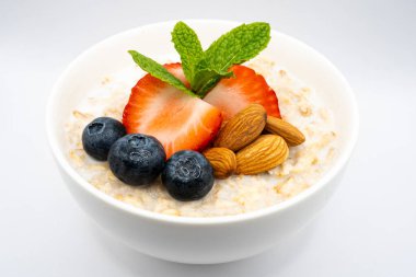 Üzerinde çilek, yabanmersini, badem ve nane olan sağlıklı yulaf ezmesi. Lezzetli ve besleyici bir kahvaltı. Yüksek kalite fotoğraf