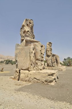 Memnon Heykeli. Firavun Amenhotep III 'ün yıkılmış Amenhotep III Cenaze Tapınağı' nın önünde duran iki büyük taş heykel.