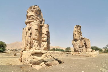 Memnon Heykeli. Firavun Amenhotep III 'ün yıkılmış Amenhotep III Cenaze Tapınağı' nın önünde duran iki büyük taş heykel.