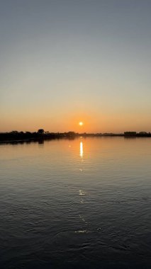 Sakin altın güneş ışığı huzurlu bir günbatımında huzur dolu bir manzara yaratarak güzel bir şekilde nehri yansıtır. Yumuşak ışık nehrin nazik akışını güçlendirir. Bu yüksek çözünürlüklü fotoğraf barışın özünü yansıtıyor..