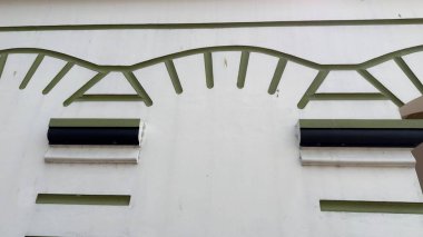 Çağdaş tasarım için karmaşık yeşil dalgalı süsleme ve ince mimari öğeler içeren kapalı-beyaz duvar bölümünü süsleyin.