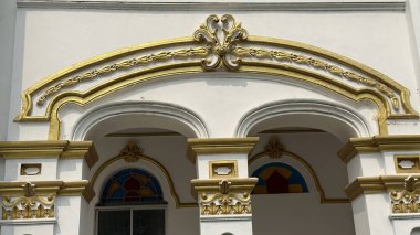 Karmaşık altın parşömen zarif beyaz bir kemeri süslüyor, klasik mimari güzelliği ve ayrıntılı işçiliği bir bina üzerinde sergiliyor..