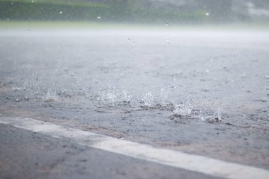 Şiddetli yağmurun yol yüzeyine düşüşünü yakından görmek, su damlacıklarını yakalamak ve fırtınalı bir atmosferde hareket etmek, doğa arka plan kavramı..