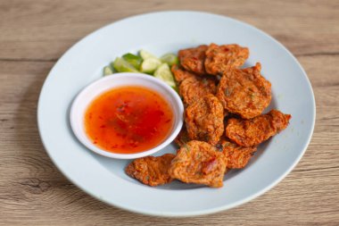 Kızarmış balık köftesi, soslu ve tabakta servis edilen salatalıklı. Orta Tayland yemekleri.