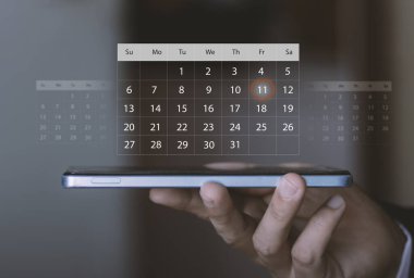 Planlama, hatırlatıcılar, zaman yönetimi, mobil verimlilik ve akıllı kişisel organizasyon. Dijital takvim kaplamalı akıllı telefon kullanan kişi, önemli bir tarihi vurgular.