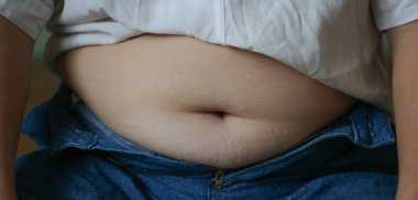 Kilo alma, obezite riski, kötü beslenme alışkanlıkları ve modern oturma düzeniyle ilgili sağlık sorunları. Şişman göbeğini, düğmesiz kotunu, şişman vücudunu ve sağlıksız yaşam tarzını kapat..