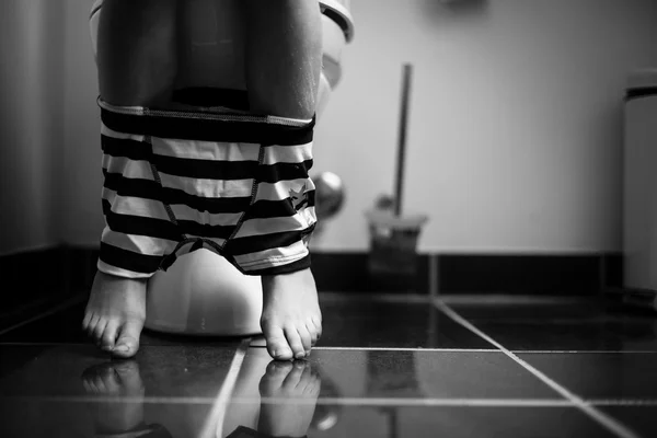 Sous-vêtements autour des jambes d'un jeune garçon sur une toilette — Photo