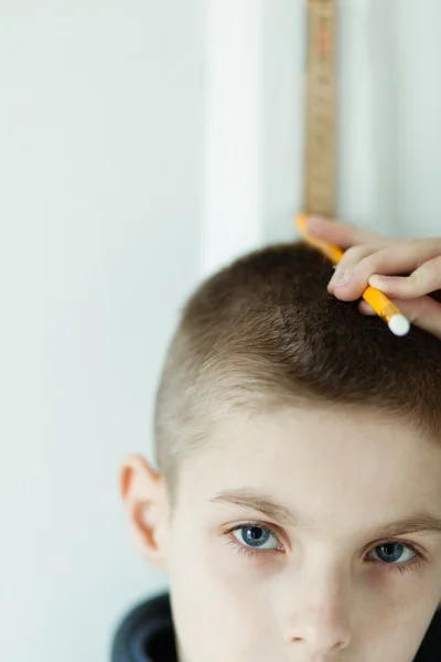 Ragazzo che tiene la matita sulla testa per controllare l'altezza — Foto Stock