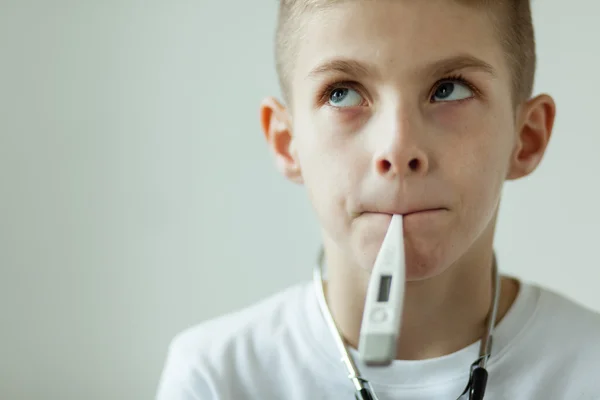 Ragazzo premuroso con termometro digitale in bocca — Foto Stock