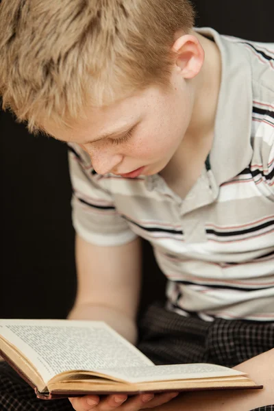 Single boy sitting and reading a book — Stock Photo, Image