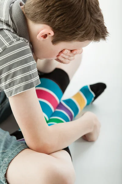 Truchlící chlapec sedí se zkříženýma nohama pokrývá oči — Stock fotografie