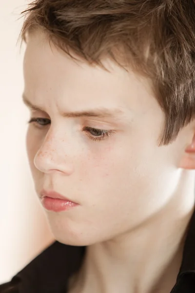 Ernstige jongen met een rommelige bruin haar fronsen — Stockfoto