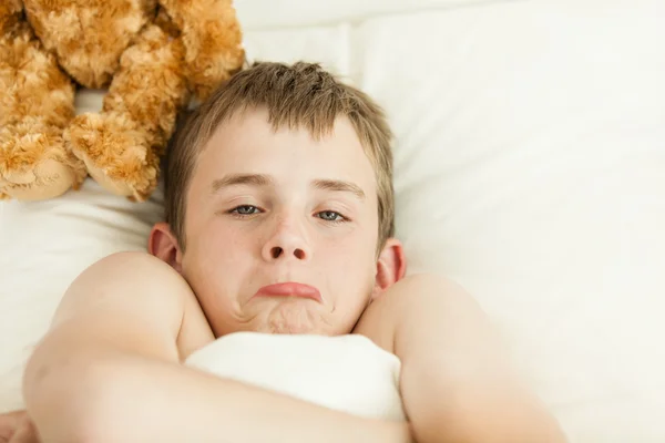 Chico de pucheros en cama cubierto con manta —  Fotos de Stock