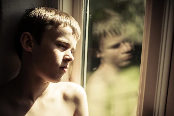 Trauriges Kind ohne Hemd spiegelt sich im Fenster — Stockfoto