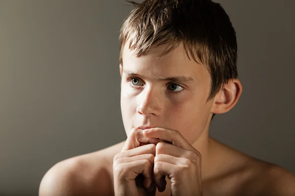 Задумчивый мальчик с руками перед ртом — стоковое фото