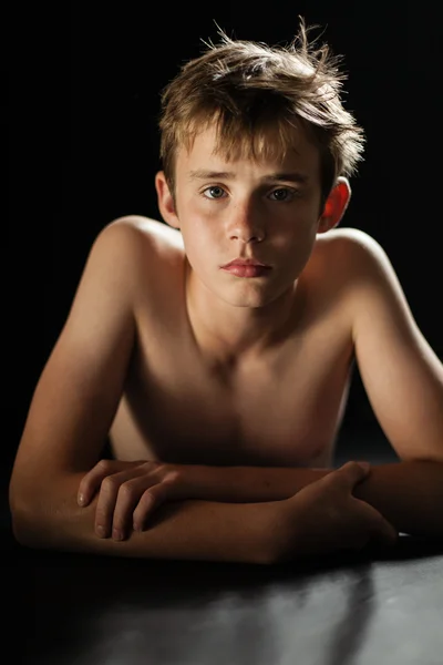 Молодий без сорочки підліток хлопчик лежить на стомасі на підлозі — стокове фото