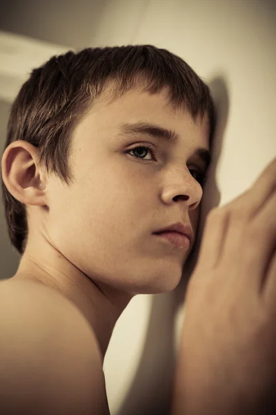 Ung tonåring pojke med örat tryckt mot väggen — Stockfoto