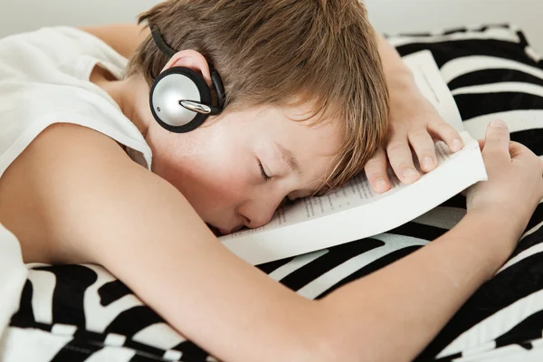 Boy with headphones asleep on top of textbook — Stock Photo, Image