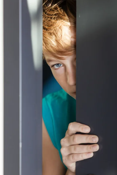 Grave giovanissima peeking da tra porta e parete — Foto Stock