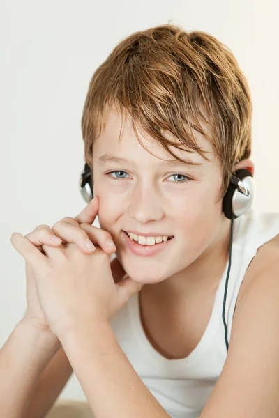 Lindo chico sonriendo mientras escucha los auriculares — Foto de Stock