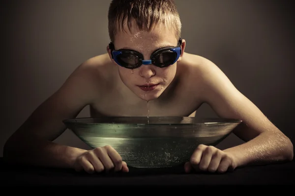 Junge in Schutzbrille mit Gesicht über Wasserschale — Stockfoto