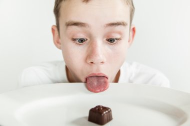 Boy sticks his tongue over rim of plate clipart