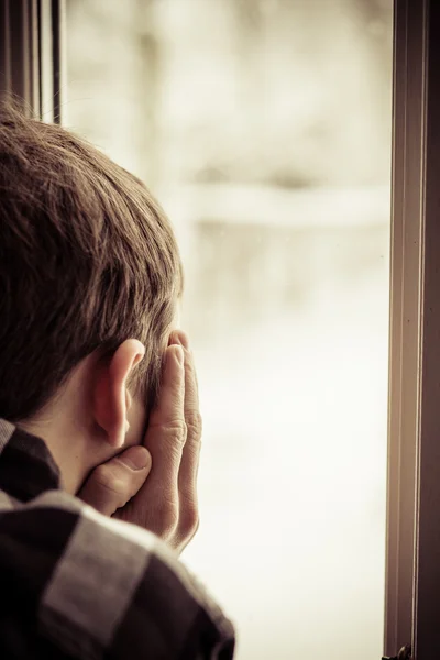 Visão traseira do menino olhando para fora da janela — Fotografia de Stock