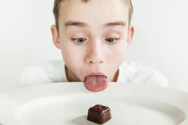 Boy sticks his tongue over rim of plate — Stock Photo, Image