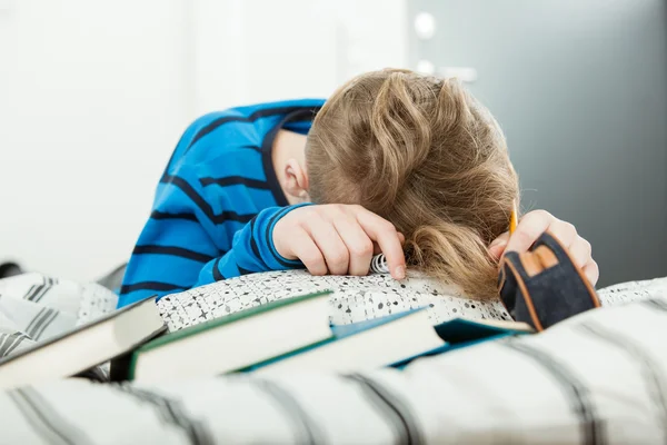 Exhausted young boy asleep on his text books — Stock Photo, Image