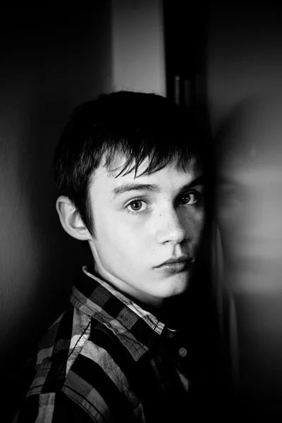 Grave adolescente menino escondido atrás da porta em casa — Fotografia de Stock