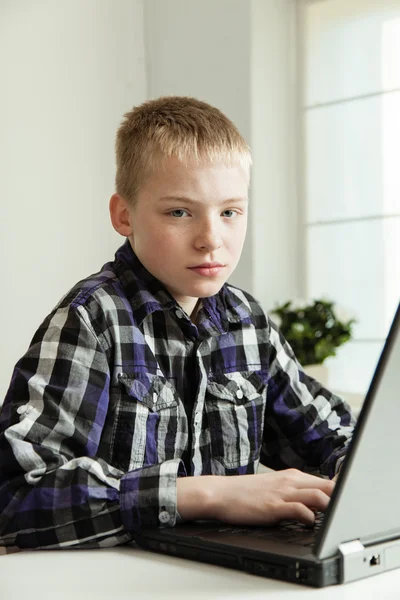 Mladí dospívající chlapec sedí u stolu s notebookem — Stock fotografie