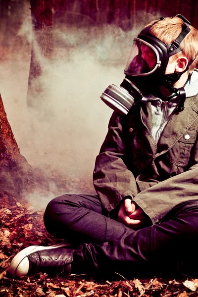 Boy in gas mask surrounded by fog — Stock Photo, Image