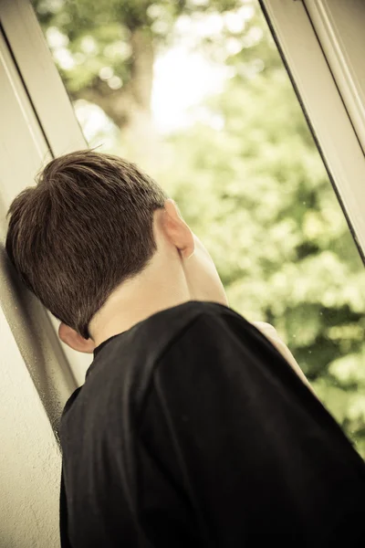 Vue arrière du garçon adolescent regardant par la fenêtre — Photo