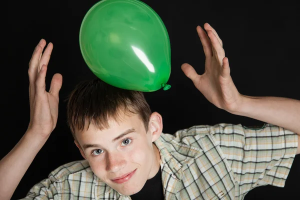 Smiling Teen Boy Playing with Bright Green Balloon