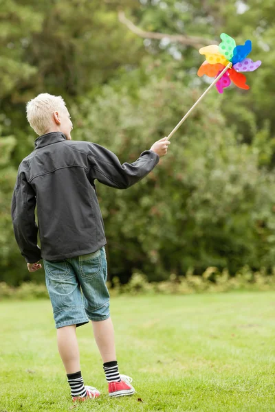 Pojke bär svart jacka rymmer färgglada snurra — Stockfoto