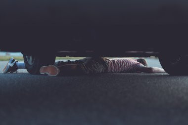 Unconscious child stuck underneath car clipart