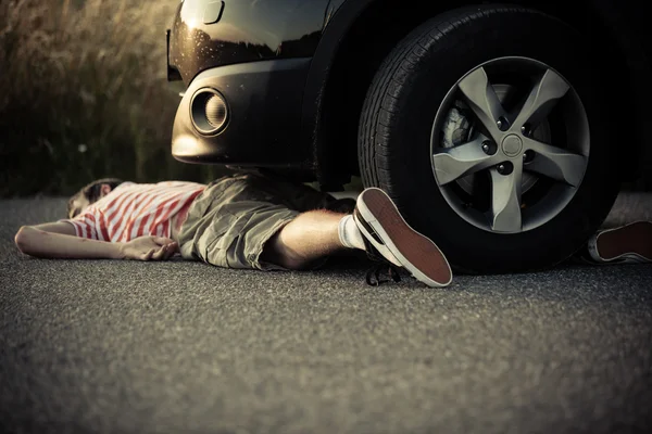 Dead child laying on street in front of car