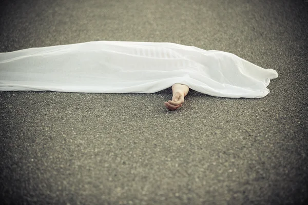 Dead body covered with sheet and hand sticking out — Stock Photo, Image