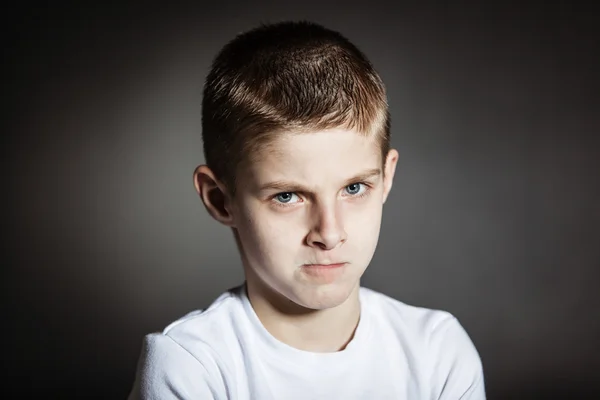 Boos mannelijk kind poseren pensief in donkere kamer — Stockfoto