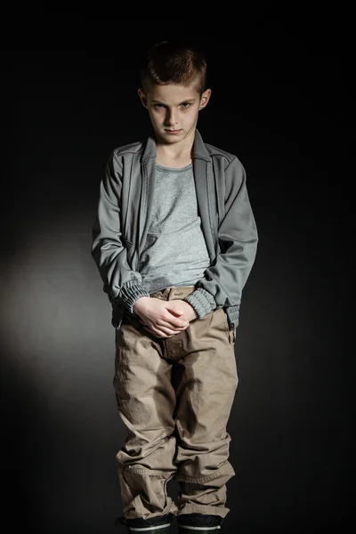 Angry boy wearing oversized clothes in dark room — Stock Photo, Image